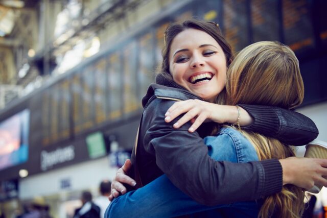 2 jeunes femmes s'étreignent dans une gare